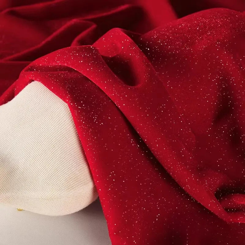 Une longueur de Tissu velours pailleté au mètre de Longan Craft France, un doux tissu velours polyester argenté scintillant, est drapée sur le bras d'un mannequin blanc - idéal pour les robes de soirée, la couture ou la décoration.