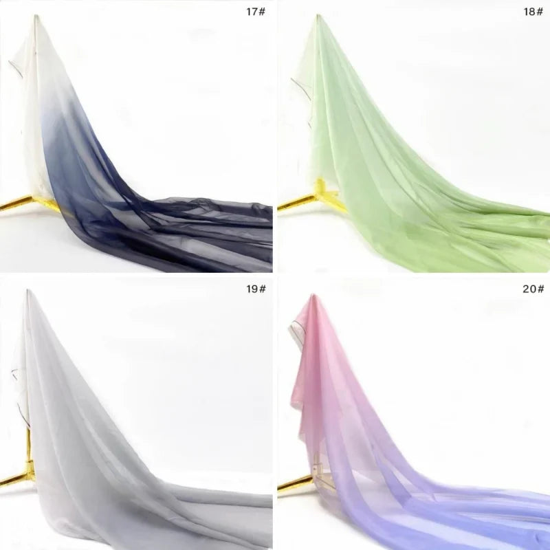 Quatre panneaux de Mousseline transparente dégradée au mètre de Longan Craft France - bleu foncé à blanc, vert clair, gris et rose passant au violet - sont présentés sur des présentoirs ; chaque panneau capte magnifiquement la lumière.