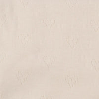 Gros plan sur le tissu pointelle jacquard en forme de cœur beige clair de Longan Craft France, un fin tricot d'été au mètre, idéal pour le bricolage de vêtements pour bébés et enfants avec ses délicats trous en forme de cœur.