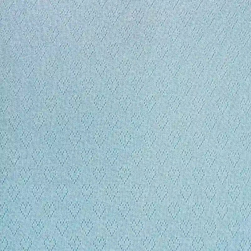 Le Tissu pointelle cœur au mètre de Longan Craft France présente une surface texturée bleu pâle avec de délicats motifs de diamants - idéal pour des couches de base et des vêtements d'intérieur élégants.
