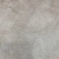 Gros plan sur une surface légère et texturée avec un motif irrégulier, similaire au tissu suédine imprimé au mètre-velours suédine motif litchi de Longon Craft France, parfait pour les manteaux, les canapés ou les projets de bricolage.