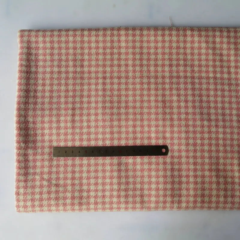 Un morceau de tissu flanelle mammouth pied-de-poule au mètre de Longan Craft France est posé à plat, avec une flanelle pied-de-poule rose et blanche, et une règle en métal sur le dessus pour l'échelle.