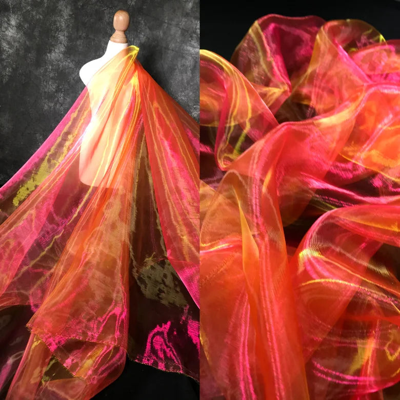 Le Tissu organza irisé au mètre de Longan Craft France, présenté en rose, orange et jaune éclatants, est drapé sur une robe. Un gros plan met en évidence la texture transparente de l'organza cristallin et les couleurs vives.