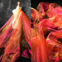 Le Tissu organza irisé au mètre de Longan Craft France, présenté en rose, orange et jaune éclatants, est drapé sur une robe. Un gros plan met en évidence la texture transparente de l'organza cristallin et les couleurs vives.