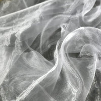 Un gros plan de Tissu organza irisé au mètre de Longan Craft France révèle son organza cristal blanc translucide aux plis doux et à la brillance subtile, idéal pour les projets de couture et de décoration élégants.