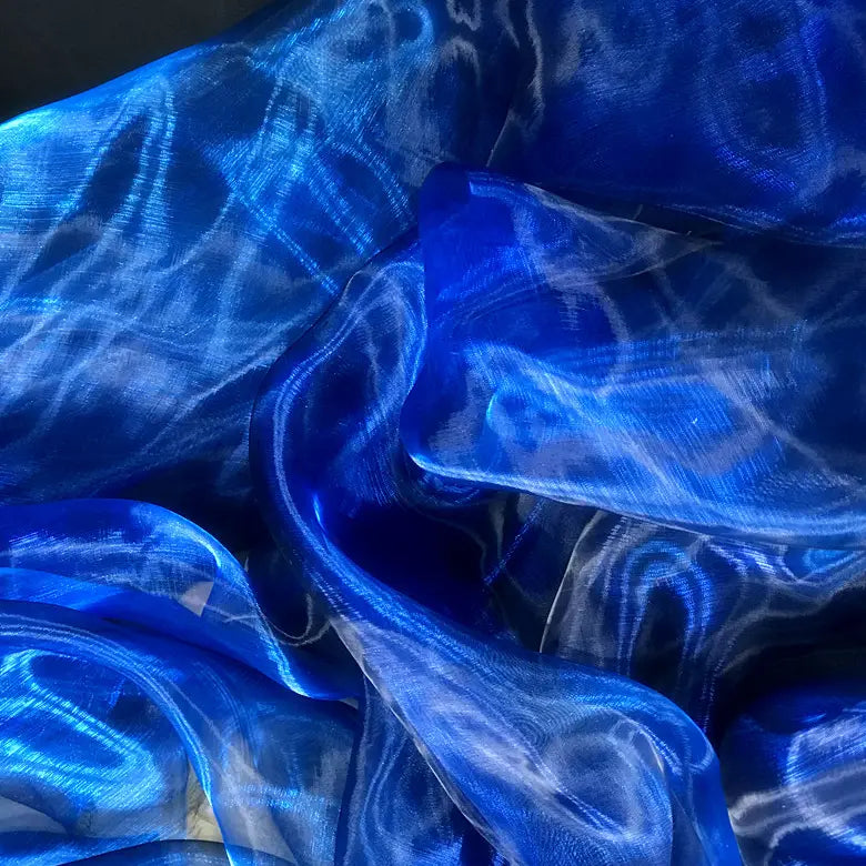 Tissu organza irisé au mètre de Longan Craft France : une matière transparente bleu, drapée et plissée, crée des reflets ondoyants et des nuances bleutées idéales pour robes en organza cristal.