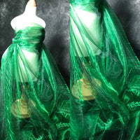 Un mannequin de couturière est drapé dans le Tissu organza irisé au mètre de Longan Craft France, un tissu transparent organza vert émeraude cristal. La matière translucide s'écoule élégamment jusqu'à la base, montrée sous deux angles.