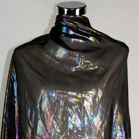Un mannequin présente Mousseline irisée au mètre, une mousseline de polyester métallisée de Longan Craft France, qui scintille de nuances arc-en-ciel sous la lumière. Le fond reste uni et neutre, idéal pour mettre en valeur ce tissu DIY.