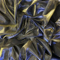 Un gros plan sur un tissu froissé, semi-transparent et métallisé noir et or montre la brillance subtile et la surface texturée du Tissu en tulle bicolore irisé au mètre de Longan Craft France - idéal pour une robe de soirée scintillante.