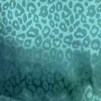 Gros plan sur le tissu satin jacquard léopard au mètre de Longan Craft France, un tissu animalier multicolore en polyester avec des taches irrégulières de léopard - parfait textile satiné pour chemises DIY.