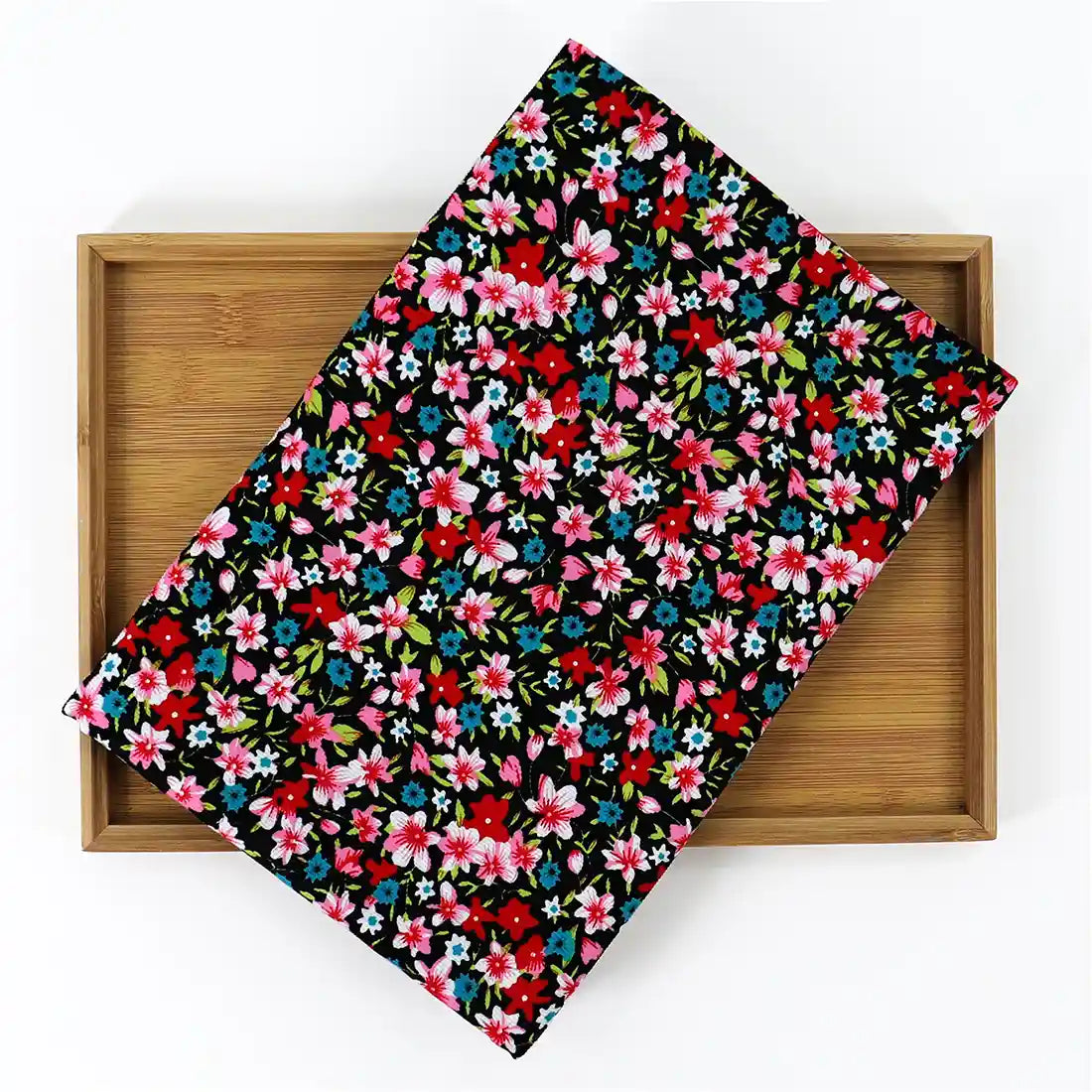 Un plateau rectangulaire en bambou est recouvert de velours côtelé coton imprimé lys de Longan Craft France, un tissu fin en velours côtelé avec un motif floral coloré de lys rouges, roses, bleus et blancs avec des feuilles vertes.