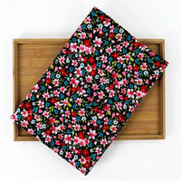 Un plateau rectangulaire en bambou est recouvert de velours côtelé coton imprimé lys de Longan Craft France, un tissu fin en velours côtelé avec un motif floral coloré de lys rouges, roses, bleus et blancs avec des feuilles vertes.