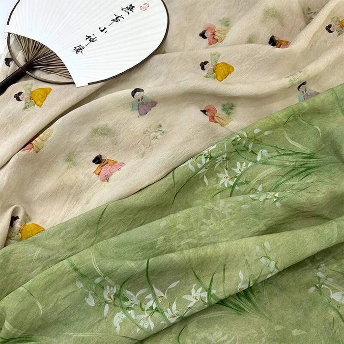 Un Tissu en lin lyocell au mètre de Longan Craft France, orné de figures traditionnelles colorées, est associé à un tissu chinois de style vert ; un éventail en papier plié avec des caractères chinois repose sur le tissu crème.