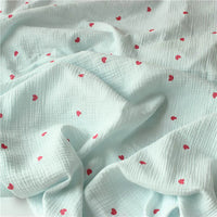 Tissu double gaze petit cœur au mètre de Longan Craft France : crêpe doux 100% coton avec une texture quadrillée bleu clair et des motifs de cœurs rouges éparpillés, parfait pour des plis doux et un look délicat et texturé.