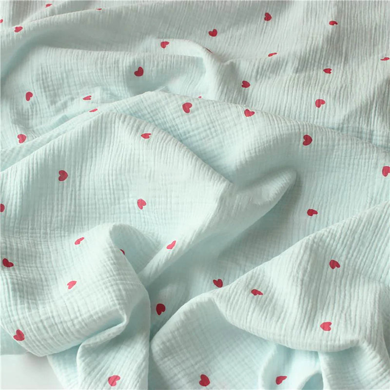 Tissu double gaze petit cœur au mètre de Longan Craft France : crêpe doux 100% coton avec une texture quadrillée bleu clair et des motifs de cœurs rouges éparpillés, parfait pour des plis doux et un look délicat et texturé.