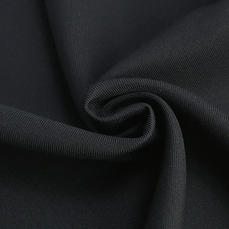 Gros plan sur Tissu gabardine à finition mate au mètre de Longan Craft France, un textile noir uni à armure sergée, partiellement plié et tordu pour montrer son drapé élégant et sa surface lisse, idéal pour vestes.