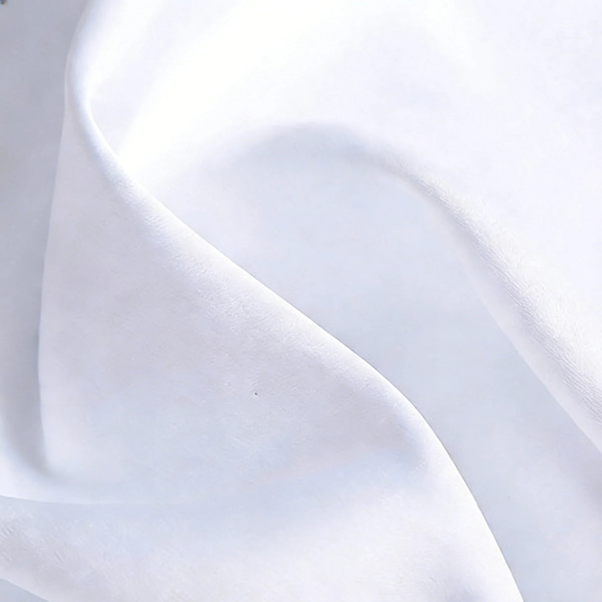 Gros plan sur le Tissu satin blanc uni au mètre de Longan Craft France, un textile de satin de polyester aux plis doux et aux ombres subtiles, idéal pour les robes et les vêtements élégants.