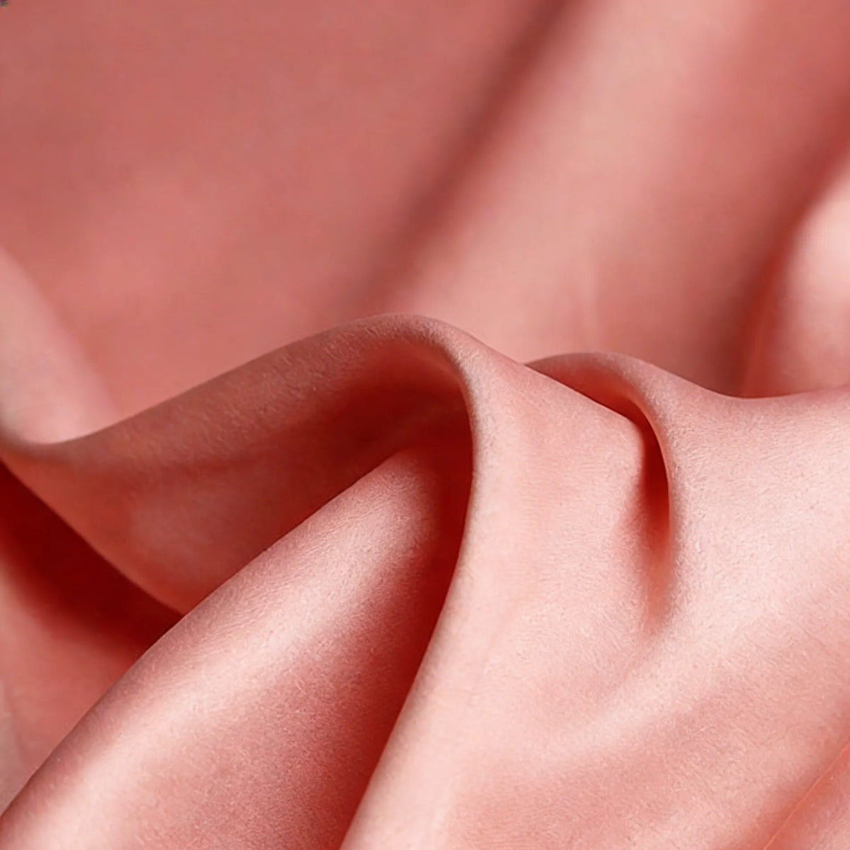 Gros plan sur le Tissu satin mat uni au mètre de Longan Craft France : un satin de polyester pêche doux et lisse, parfait pour les robes et les vêtements élégants, avec des plis doux et une brillance subtile.