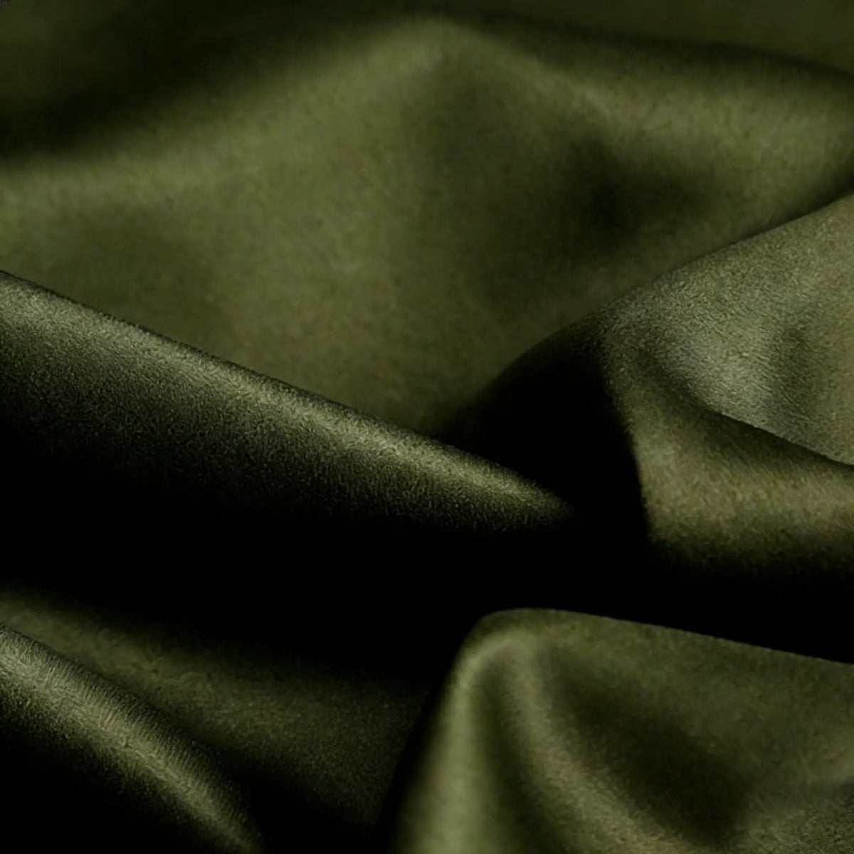 Gros plan sur le Tissu satin mat uni au mètre de Longan Craft France, un satin de polyester lisse et vert foncé idéal pour les vêtements élégants, présentant des plis visibles et un léger éclat.