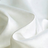 Gros plan sur un tissu satiné blanc mat et lisse de Longan Craft France, révélant des plis doux et une brillance subtile - un textile polyester idéal pour les robes et les vêtements élégants.