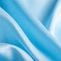 Gros plan sur le tissu satin mat uni au mètre bleu clair de Longan Craft France, qui présente des plis délicats et des ombres douces - un textile en satin de polyester parfait pour les robes de chambre et les vêtements élégants.