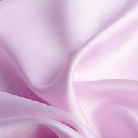 Gros plan sur le Tissu satin mat uni au mètre de Longan Craft France, un textile lisse en satin de polyester rose pâle aux plis doux et à la texture brillante, idéal pour les robes et les vêtements élégants.