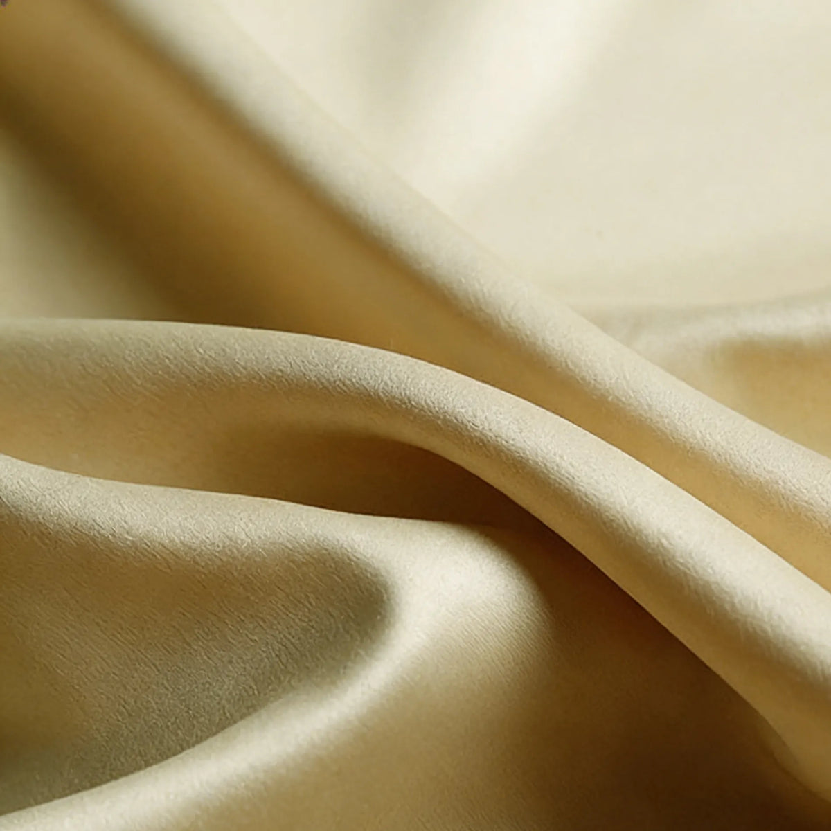 Gros plan sur le "Tissu satin mat uni au mètre" de Longan Craft France en or clair, mettant en valeur ses plis de polyester lisses et doux et son drapé délicat - le textile satin idéal pour la confection de robes et de vêtements élégants.