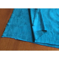 Un morceau de tissu microfibre suédine de Longan Craft France, vendu au mètre, avec des bords non finis, repose sur une surface brune. Un coin est replié, montrant le dessous doux et extensible dans les 4 sens - idéal pour les projets de vêtements de bricolage.