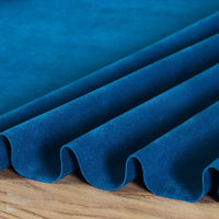 La Matière suédine microfibre au mètre de Longan Craft France est un tissu doux et extensible avec une brillance moelleuse, magnifiquement drapé en plis réguliers sur du bois, mettant en valeur sa couleur riche - idéal pour les projets de vêtements DIY.