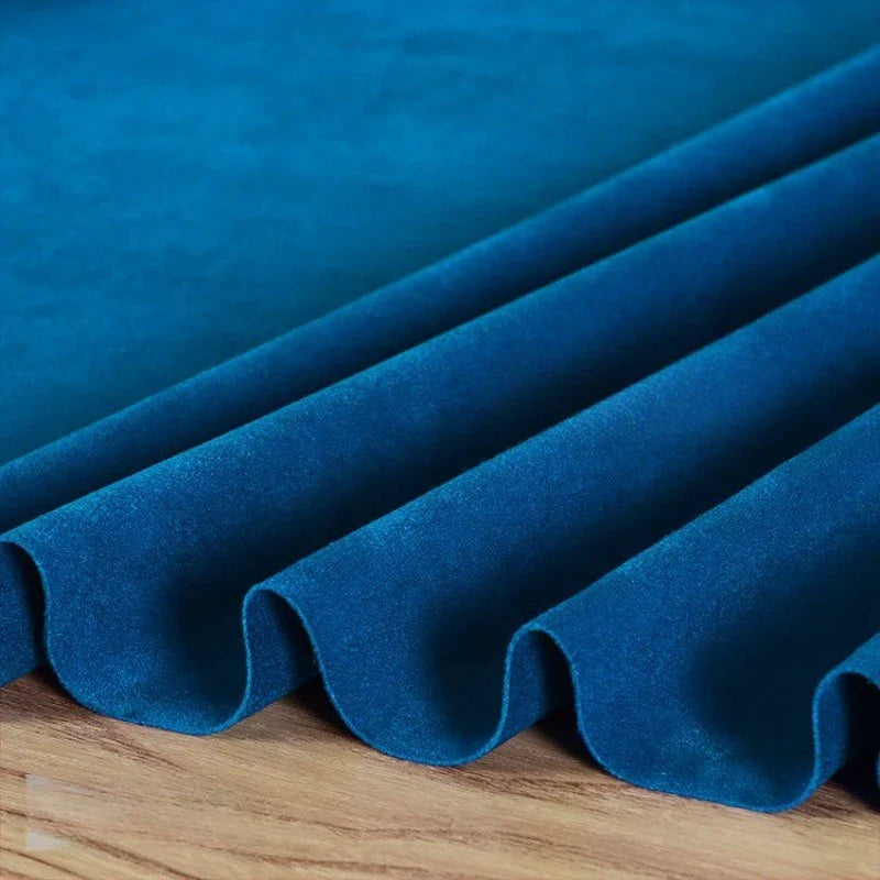 La Matière suédine microfibre au mètre de Longan Craft France est un tissu doux et extensible avec une brillance moelleuse, magnifiquement drapé en plis réguliers sur du bois, mettant en valeur sa couleur riche - idéal pour les projets de vêtements DIY.
