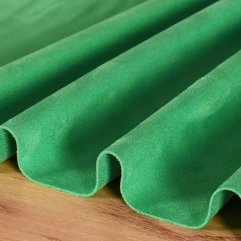 La Matière suédine microfibre au mètre de Longan Craft France, un tissu extensible dans les quatre sens, doux et velouté, destiné aux vêtements DIY, est élégamment drapée en douces vagues sur une surface en bois.