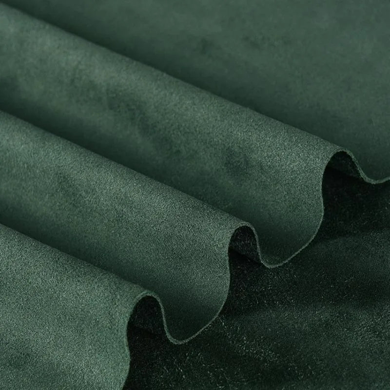 Gros plan sur la Matière suédine microfibre au mètre de Longan Craft France, un tissu vert foncé, extensible dans les 4 sens. La micro-suède apparaît lisse et veloutée dans des plis doux et régulièrement espacés, ce qui est parfait pour les projets de bricolage de vêtements.