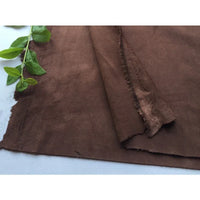 Un morceau de Matière suédine microfibre au mètre de Longan Craft France, un tissu micro suédine doux et extensible en 4 directions pour le bricolage de vêtements, est posé à plat sur une surface blanche, ses bords non finis révélant sa texture unique.