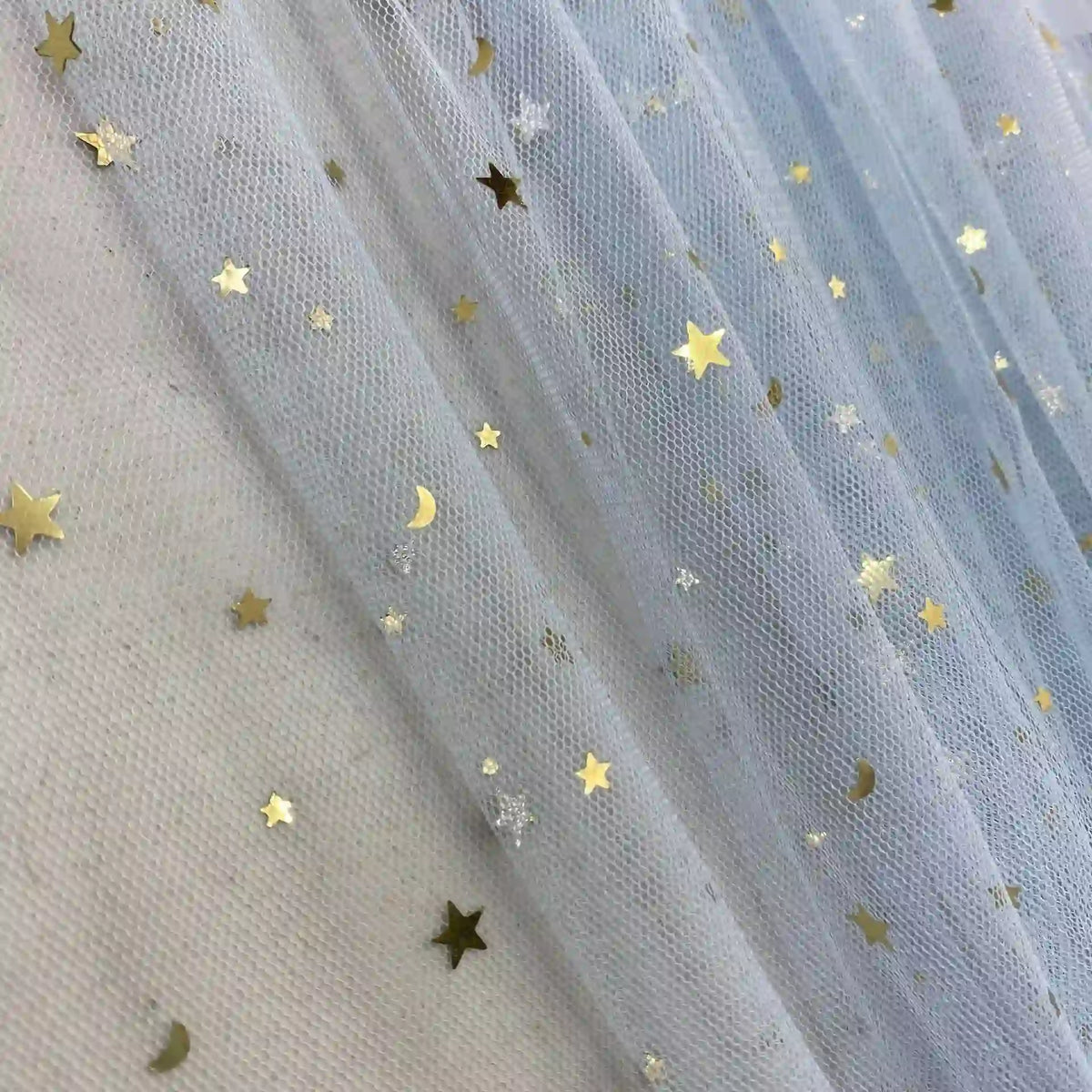 Le Tissu tulle lune et étoiles au mètre de Longan Craft France est un tulle pailleté multicolore orné d'étoiles et de lunes métalliques, idéal pour les costumes de scène, les robes ou les robes de chambre éthérées.