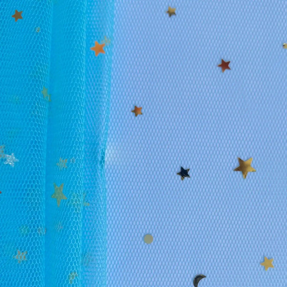 Le Tissu tulle lune et étoiles au mètre de Longan Craft France, un filet bleu avec des paillettes multicolores et des étoiles or/noires, est présenté sur une surface texturée blanche, avec des confettis éparpillés sur le tulle et le fond.