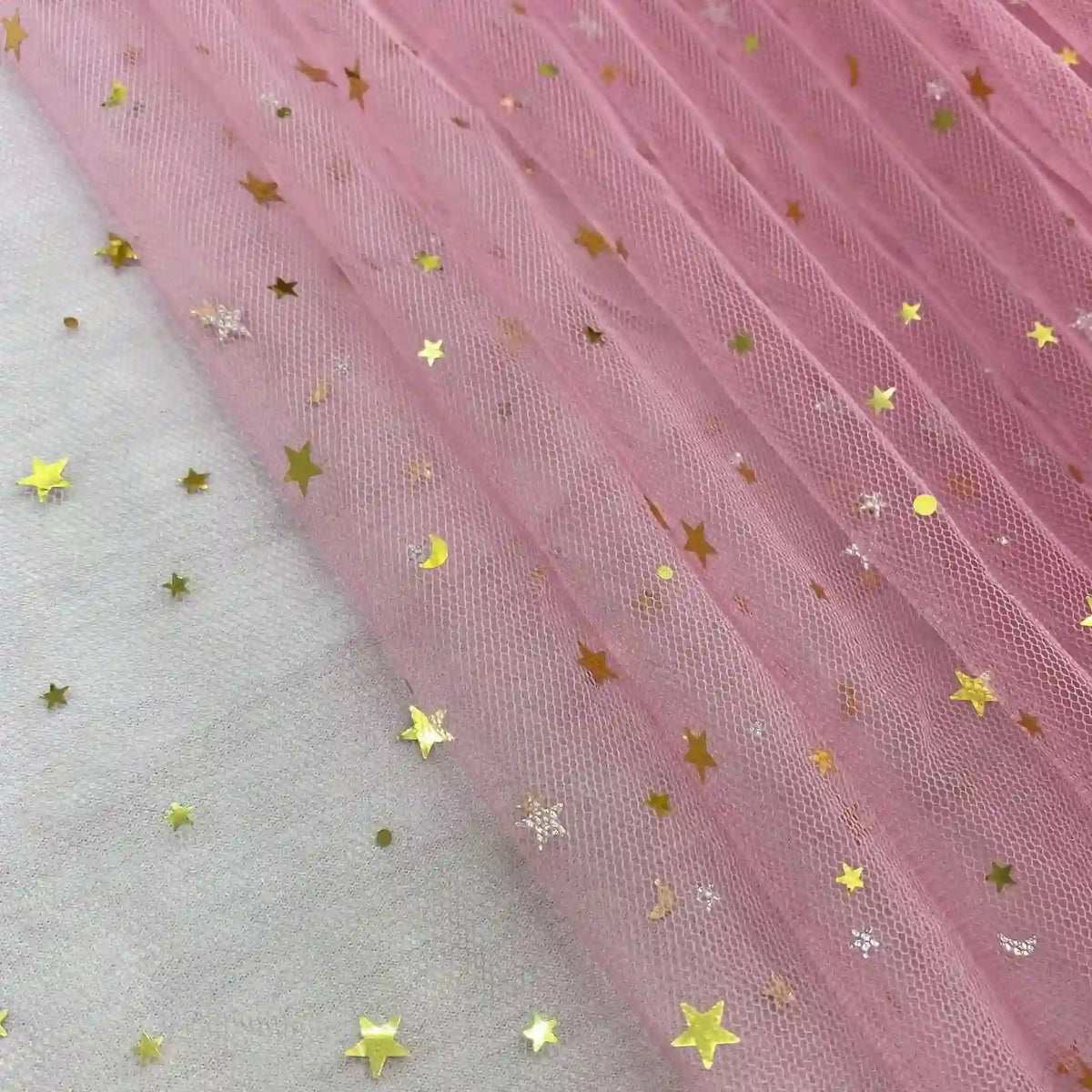 Le Tissu tulle lune et étoiles au mètre de Longan Craft France est un tulle multicolore pailleté, idéal pour les costumes de scène ou projets créatifs, orné de sequins étoiles et points dorés sur fond rose.