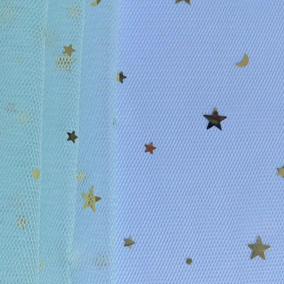 Gros plan sur le "Tissu tulle lune et étoiles au mètre" de Longan Craft France, un tissu de tulle pailleté multicolore idéal pour les costumes de scène, superposé sur une surface et décoré de confettis d'étoiles et de lunes dorées.
