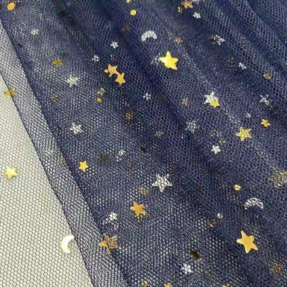 Gros plan sur le tissu tulle lune et étoiles au mètre de Longan Craft France, une maille pailleté multicolore transparente ornée de paillettes étoiles et lunes dorées et argentées, parfaite pour les costumes de scène et les effets de superposition.