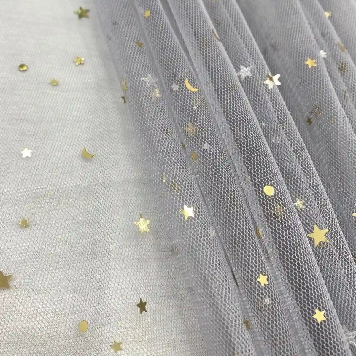 Le "Tissu tulle lune et étoiles au mètre" de Longan Craft France est un tulle pailleté multicolore, idéal pour les costumes de scène, qui présente des étoiles et des croissants de lune métalliques éparpillés sur un tissu doux et drapé.