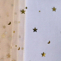 Gros plan sur le Tissu tulle lune et étoiles au mètre de Longan Craft France en beige transparent avec des motifs d'étoiles et de croissants dorés à gauche, à côté d'un pailleté de tulle en maille blanche orné d'étoiles multicolores scintillantes.