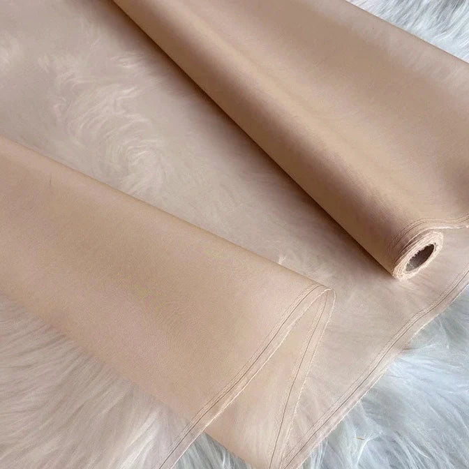 Un rouleau d'Organza de soie multicolore 8 momme de Longan Craft France, fabriqué à partir de pure soie de mûrier, est partiellement déroulé sur une surface blanche. Ce tissu luxueux est léger, translucide et ses bords sont lisses.