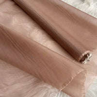 Gros plan sur l'Organza de soie multicolore 8 momme au mètre de Longan Craft France, tissu en pure soie de mûrier, déroulé sur une surface en fourrure blanche ; on voit sa texture diaphane et légèrement brillante ainsi que son extrémité partiellement effilochée.