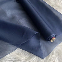 Un rouleau d'Organza de soie multicolore 8 momme de Longan Craft France, fabriqué à partir de pure soie de mûrier, est partiellement déroulé sur une surface duveteuse. Ce tissu léger et luxueux est translucide et révèle sa texture.