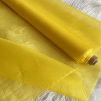 Un rouleau d'Organza de soie multicolore 8 momme au mètre de Longan Craft France, fabriqué à partir de pure soie de mûrier, est partiellement déroulé sur une surface blanche. Ce tissu de luxe semble léger et translucide.