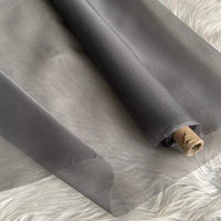 Un rouleau d'Organza de soie multicolore 8 momme au mètre de Longan Craft France est partiellement déroulé sur une surface texturée, révélant son tissu lisse et translucide en pure soie de mûrier et le tube en carton à l'une de ses extrémités.