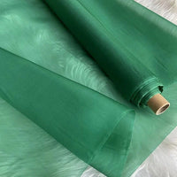 Un rouleau de Longan Craft France Organza de soie multicolore 8 momme en pure soie de mûrier est partiellement déroulé, montrant son aspect translucide et luxueux-idéal pour créer des robes élégantes.