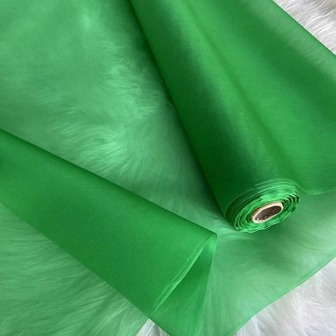 Un rouleau d'Organza de soie multicolore 8 momme au mètre de Longan Craft France, pure soie de mûrier pour robes de luxe, est partiellement déroulé sur une surface douce. Le tissu est léger et translucide.