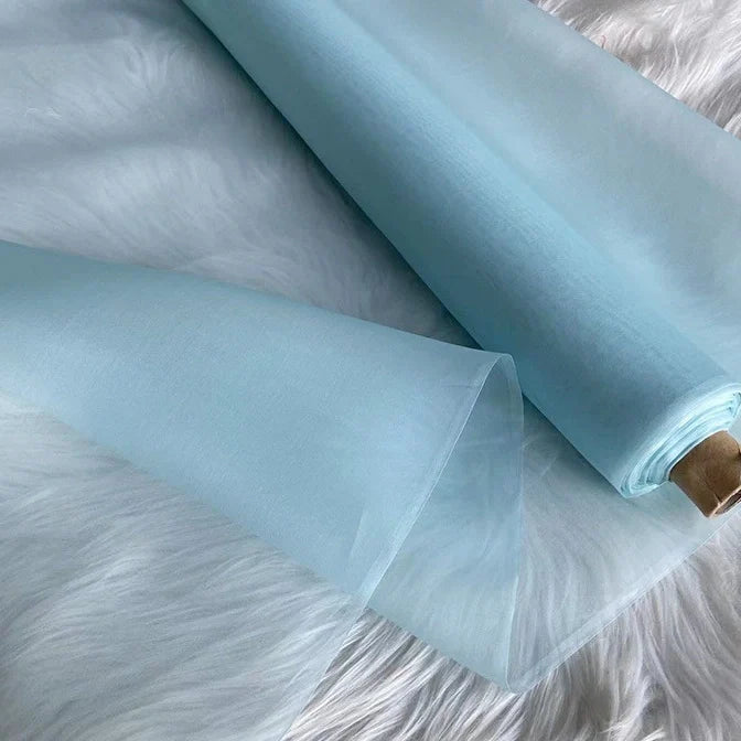 Un rouleau d'Organza de soie multicolore 8 momme de Longan Craft France, fabriqué à partir de pure soie de mûrier, est partiellement déroulé sur une surface blanche et douce. Sa texture lisse et délicate est parfaite pour créer des robes de soirée luxueuses.