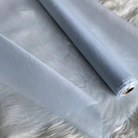 Un rouleau d'Organza de soie multicolore 8 momme au mètre de Longan Craft France, en pure soie de mûrier, est déroulé sur une surface texturée blanche. Ce tissu luxueux, fin et translucide est idéal pour les robes élégantes et les robes du soir.