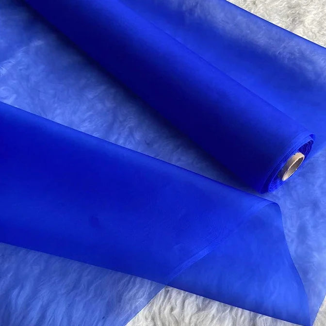 Un rouleau d'Organza de soie multicolore 8 momme de Longan Craft France est présenté sur une surface blanche. Ce tissu en pure soie de mûrier est léger, légèrement transparent et idéal pour créer des robes de luxe et des robes de soirée élégantes.